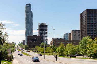 Ottawa, Canada - May 18, 2022: Cityscape with buildings, construction site, traffic on road, and walking people on sidewalks in summer. City life, Carling Avenue