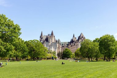 Ottawa, Kanada - 18 Mayıs 2022: Baharda Majors Hill Park 'ta insanlar. Şehir merkezindeki şehir parkındaki Fairmont Chateau Laurier Otel binası..