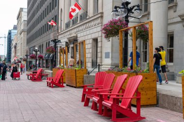 Kanada, Ottawa - 1 Temmuz 2022: Yürüyen insanlarla Sparks Caddesi ve Kanada Günü 'nde şehir merkezinde kırmızı sandalyeler. Binalarda Kanada bayrakları.