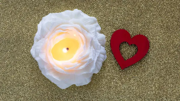 Red heart and candle in flower shape on golden background. Valentine day and love romantic concept.