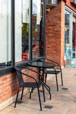 Küçük bir dükkanın önünde siyah masa ve iki sandalye. Sokak Kafesi