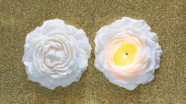 Handmade soy wax candle in flower shape on golden background. Top view of two candles.