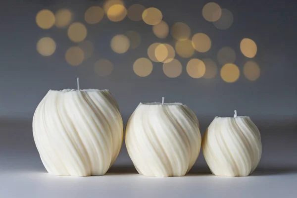 Three soy wax handmade candles of different size on white table with gray background, bokeh and copy space. Candle making craft concept.