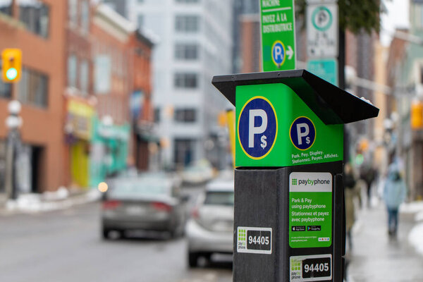 Ottawa, Canada - January 23, 2023: Parking meter on city street with cars on road. Pay by phone available
