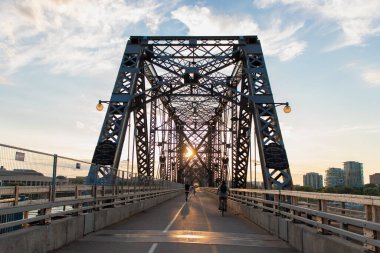 Ottawa, Kanada - 4 Haziran 2024: Alexandra Köprüsü Ottawa, Ontario 'dan Quebec' teki Gatineau şehrine kadar bisikletli ve gün batımında yolda olan insanlar