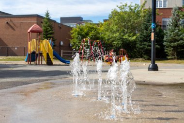 Splash pad playground in public park in summer without people. Fountain with splashing water on a sunny day.