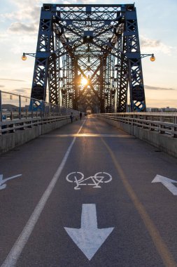 Ottawa, Canada - June 4, 2024: Alexandra Bridge from Ottawa, Ontario to Gatineau city of Quebec with walking people during sunset. Bicycle lane clipart