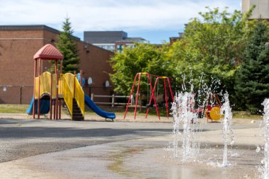 Splash pad playground in public park in summer without people. Fountain with splashing water on a sunny day.