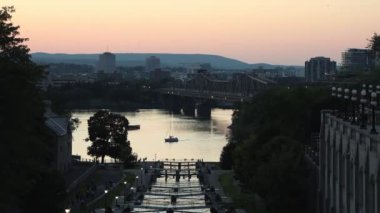 Ottawa, Kanada - 31 Ağustos 2024: Ottawa, Kanada 'da Rideau kanal kilitleri. Ottawa nehri, Alexandra köprüsü ve oteli gün batımında şehir merkezinde. Yelkenli tekne