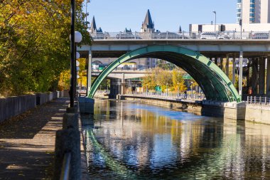 Rideau Kanalı ve sonbahar mevsiminde Ottawa, Kanada 'da sularda yansıyan bir köprü, sonbahar ağaçları ve bir patika.