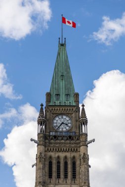 Kanada, Ottawa 'da Kanada bayrağı taşıyan parlamento binası. Bulutlu mavi gökyüzüne karşı barış kulesi.