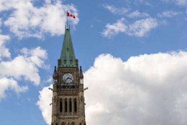 Kanada, Ottawa 'da Kanada bayrağı taşıyan parlamento binası. Bulutlu mavi gökyüzüne karşı barış kulesi.