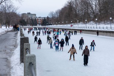 Ottawa, Kanada - 8 Şubat 2025: İnsanlar kışın Rideau Kanalı 'nda paten kayıyor. Şehir merkezindeki parlamento binası.
