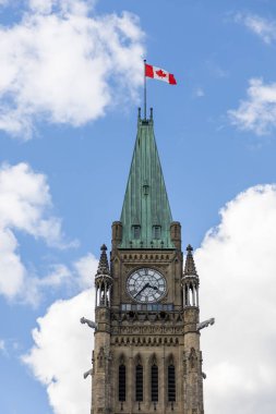 Kanada, Ottawa 'da Kanada bayrağı taşıyan parlamento binası. Bulutlu mavi gökyüzüne karşı barış kulesi.