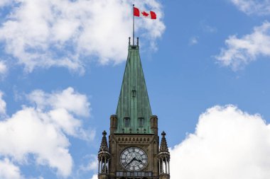 Kanada, Ottawa 'da Kanada bayrağı taşıyan parlamento binası. Bulutlu mavi gökyüzüne karşı barış kulesi.