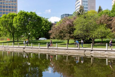 Ottawa, Kanada - 16 Mayıs 2024 Rideau Kanalı ve bisiklet yolu. Baharda şehir manzarası. Kanada başkentine park et..