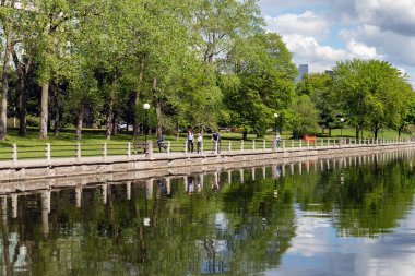Ottawa, Kanada - 16 Mayıs 2024: Rideau Kanalı ve bisiklet yolu ilkbaharda kıyı şeridi boyunca. Yürüyen ve bisiklete binen insanların olduğu bir park..