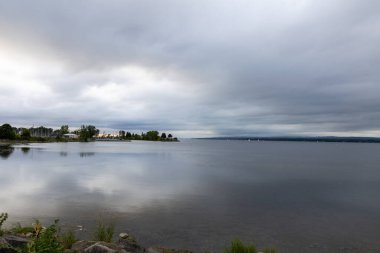 Ottawa, Kanada 'da bulutlu bir akşamda gün batımında nehir. Nehir kenarının manzarası. Bulutlu gökyüzü suya yansıyor.