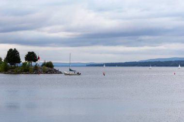 Nehir kenarında yelkenli tekneleri var. Kanada 'daki Ottawa nehri. Rıhtım manzarası ve bulutlu gökyüzü. Yatlar suyun üstünde..