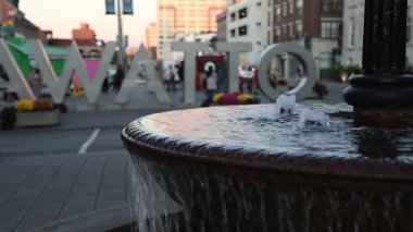 Şehir merkezindeki Byward Market bölgesindeki York Caddesi 'ndeki Millennium Fountain' den su akıyor. Kanada başkentinde Ottawa tabelasının yanında yürüyen turistler.