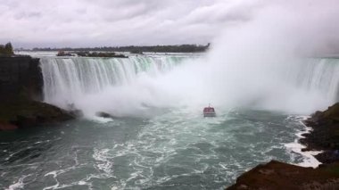 Kanada 'nın Ontario şehrinde bulutlu bir günde Niyagara Şelalesi' nde Horseshoe Şelalesi yakınlarında bir tur teknesi.