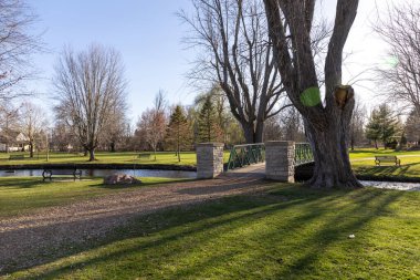 İlkbaharda derenin üzerinde köprüsü olan bir park. Stewart Park Perth, Ontario, Kanada.