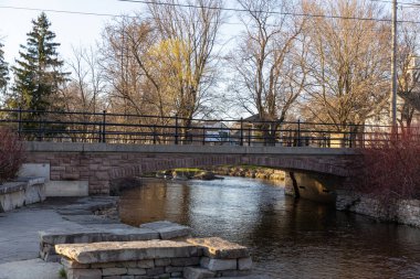 Baharda küçük bir nehrin üzerinde küçük bir taş köprü. Stewart Park Perth, Ontario, Kanada.