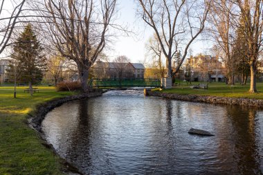 Baharda küçük bir nehrin üzerinde yaya köprüsü olan bir park. Stewart Park Perth, Ontario, Kanada.