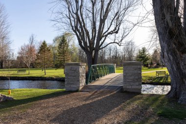 Baharda parkın manzarası ve akarsu üzerinde bir köprü. Stewart Park Perth, Ontario, Kanada.