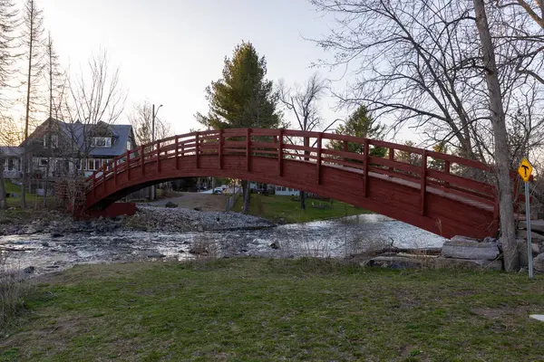 Baharda Perth, Ontario, Kanada 'da bir derenin üzerindeki kırmızı ahşap köprü