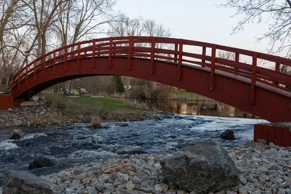 Baharda parkta bir derenin üzerindeki kırmızı köprü. Ontario, Kanada 'daki Perth kasabası.