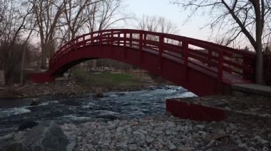 Baharda parkta bir derenin üzerindeki kırmızı köprü. Kanada, Ontario 'daki Perth kasabasında akan dere..
