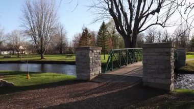 Baharda parkın manzarası ve akarsu üzerinde bir köprü. Stewart Park Perth, Ontario, Kanada.