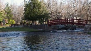 Stewart Park Perth, Ontario, Kanada. Baharda parkta bir derenin üzerinde küçük kırmızı bir köprü..