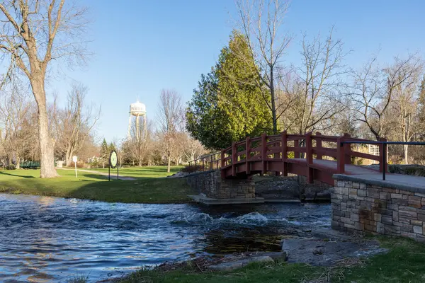 Perth, Kanada -27 Nisan 2025: Stewart Park Perth, Ontario, Kanada ilkbaharda. Nehrin üzerinde kırmızı tahta köprü