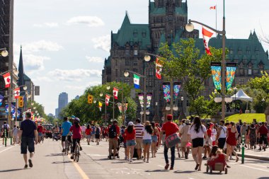 Kanada, Ottawa - 1 Temmuz 2024: Kanada Günü şehir merkezinde. Parlamento Tepesi yakınlarındaki Wellington caddesinde kırmızı giysiler içinde yürüyen insanlar..