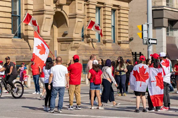 Kanada, Ottawa - 1 Temmuz 2024: Kanada Günü şehir merkezinde. Wellington caddesinde kırmızı giysiler ve Kanada bayrakları içinde yürüyen insanlar.