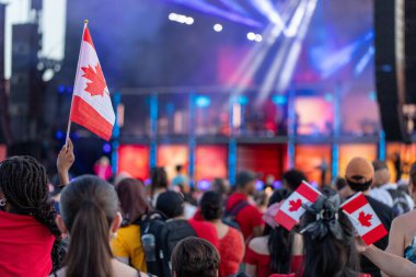 Ottawa, Ontario - 1 Temmuz 2024: Kanada Günü konseri şehir merkezinde. Sahne ışıkları ve Kanada bayraklı insanlar, kırmızı kıyafetler giyiyorlar..