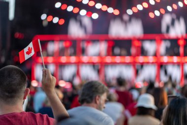 Ottawa, Ontario - 1 Temmuz 2024: Kanada Günü canlı konseri. Sahne ışıkları ve Kanada bayrakları tutan insanlar.