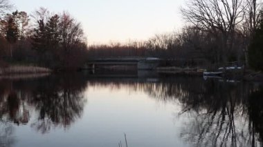 Baharda Perth, Ontario, Kanada 'da manzara. Gün batımında nehir kıyısında köprü ve sudaki ağaçların yansımaları..