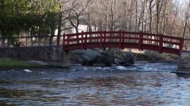 Stewart Park Perth, Ontario, Kanada. Baharda parkta bir derenin üzerinde küçük kırmızı bir köprü..