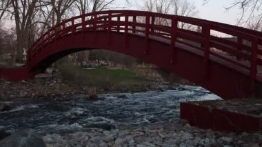 Baharda parkta bir derenin üzerindeki kırmızı köprü. Kanada, Ontario 'daki Perth kasabasında akan dere..