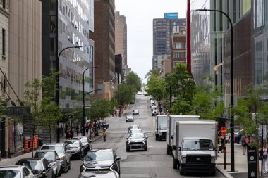 Montreal, Canada - July 4, 2025: City street urban scene in downtown in summer. Cityscape with buildings, cars and walking people