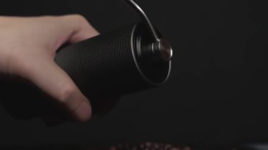 Kahve çekirdeklerini öğütmek için elle öğütücü kullanan ellerin yakın çekimi, kahve hazırlama sürecinin ve dokunsal deneyiminin vurgulanması.