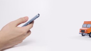Hızlı nakliye ve e-ticareti sembolize eden teslimat kamyonu ve paketlerle çevrimiçi satın almak için akıllı telefon kullanmak.