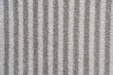 Alternatif ışık ve koyu dokulu çizgilerle yumuşak bir kumaş yüzeyinin yakın plan görüntüsü, arka plan ve dokular için uygun görsel olarak çekici nötr bir model oluşturur..