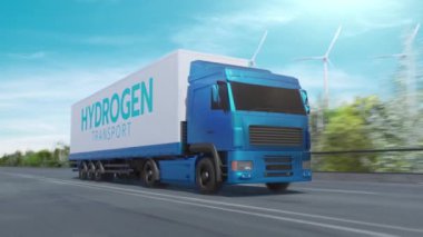 Hidrojenle çalışan bir kamyon otoyolda temiz enerji ve çevre dostu lojistiği sembolize eden rüzgâr türbinleri taşıyan mallar taşıyor..