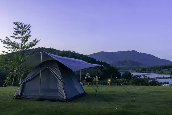 Yüksek dağ alacakaranlık günbatımında, yağmur ormanlarından gri tentelerle gri çadır kurarak dağlarda yürüyüş yapan gri çadır..