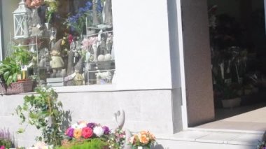 Çiçekçi dükkanının önünde satışta olan çiçekler. Kaldırımda çiçek askıları var. Çiftçilerin bitkilerini satmak. Çiçeklerden para kazanmak. Fabrika satarak para kazanıyordum. Küçük işletme kuruluşu.