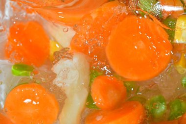 Sebzelerin yakın plan görüntüsü, havuç, bezelye, karnabahar ve su arka planında mısır. Haşlanmış sebze çorbası. Düz dizayn. Yatay resim.